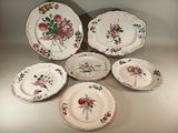 Plusieurs assiettes ornées de fleurs et de feuilles sont disposées sur une table
