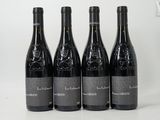 quatre bouteilles de vin sont alignées sur une surface blanche