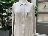 La chemise est posée sur un mannequin devant une plante en pot