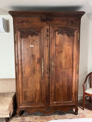 a wooden armoire in the corner of a room