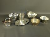 silver plated dishes and cups on a table with a spoon