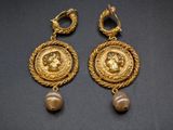 a pair of gold and pearl earrings with a head of a woman