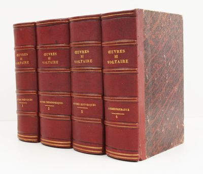quatre livres rouges sont empilés les uns sur les autres sur une surface blanche