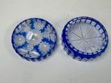 two blue glass bowls with white flowers on them on a table