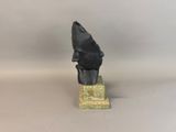 a black sculpture of a man ' s head on a marble base