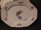 a plate with a flower design on it next to a stack of plates