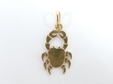une petite breloque en forme de crabe doré sur fond blanc