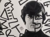 black and white photograph of a man with a hat on his head in front of a wall with graffiti