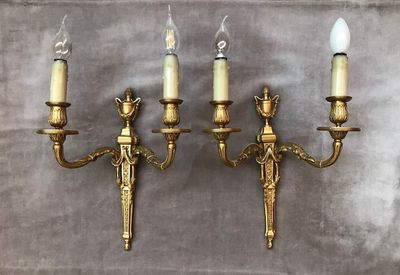 trois appliques murales en laiton vieilli avec des bougies, sur fond gris