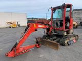 a small red excavator parked in a parking lot