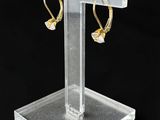 présentoir en acrylique transparent sur lequel sont disposées deux paires de boucles d'oreilles