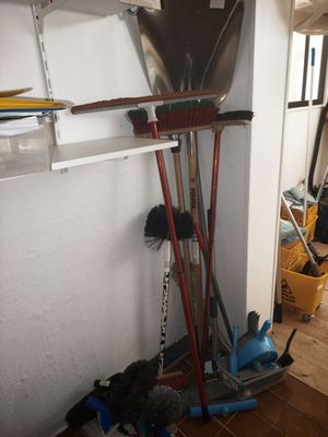 brooms, mops, and buckets are lined up against a wall in a room