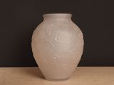 un vase blanc posé sur une table sur fond noir