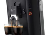 a black coffee machine with two cups of coffee in front of it