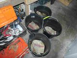 four buckets of dirt in a room with tools on the floor