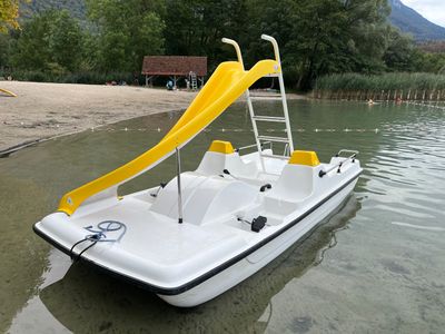 a white boat with a yellow slide in the water