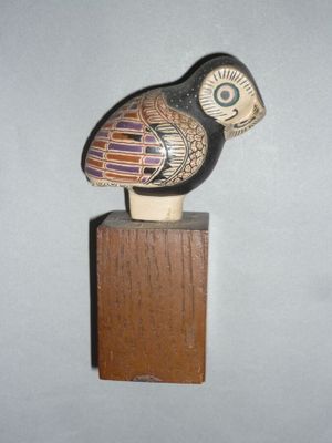 un petit objet en bois surmonté d'un oiseau