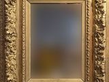 un cadre doré richement décoré, avec un miroir au centre