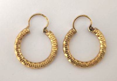 une paire de boucles d'oreilles en or sur fond blanc