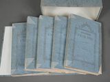 six blue books in a box with papers on top of them