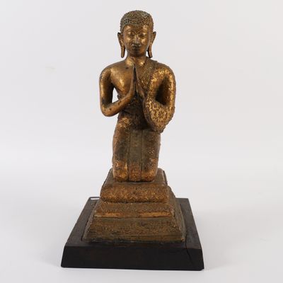 bronze statue of a person sitting on a pedestal with his hands clasped