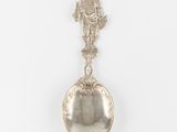un gros plan d'une cuillère en argent ornée d'une statuette