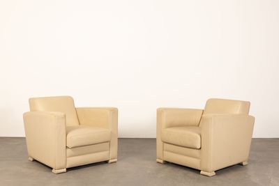 deux fauteuils en cuir beige placés l'un à côté de l'autre sur un sol en béton