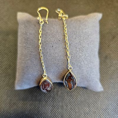 un gros plan sur une paire de boucles d'oreilles posées sur un oreiller