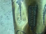 a gold vase with a design on it sitting on a table