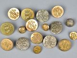 plusieurs boutons en or et en argent, ornés de symboles, sur un fond gris