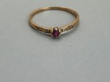 a close up of a gold ring with a red stone