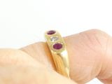 a person holding a gold ring with three stones on it