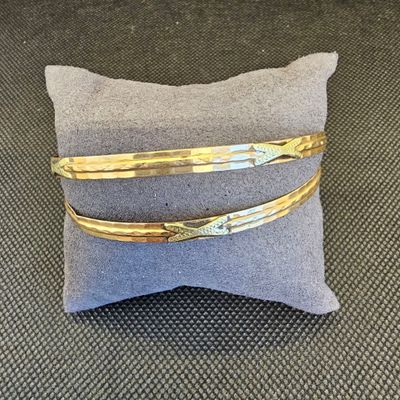 une paire de bracelets en or posés sur un oreiller