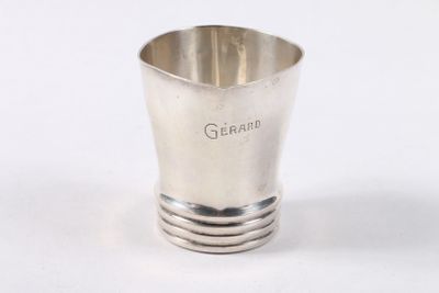 une tasse en argent posée sur une surface blanche