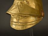 a gold helmet on a stand against a black background
