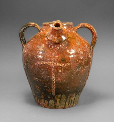 un vase marron muni d'anses, sur un fond gris