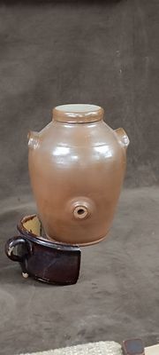a brown vase sitting on top of a bowl on the ground