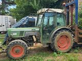un vieux tracteur vert garé dans un champ à côté d'une maison