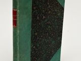 an old book with a green cover sitting on a white surface