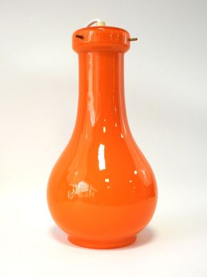 un vase orange posé sur une surface blanche