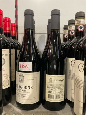 Des bouteilles de vin rouge sont alignées sur une étagère dans un magasin