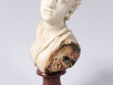 a white marble bust of a woman on a wooden stand