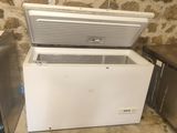 a white chest freezer sitting next to two other refrigerators