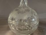 a clear glass bottle with a handle sitting on a table