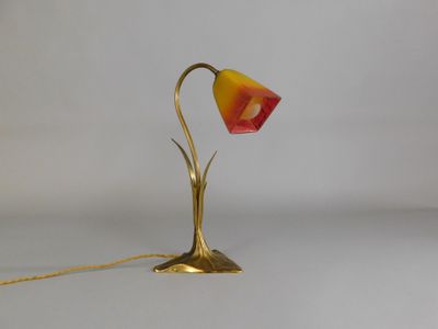 brass table lamp with a red and yellow shade on a white background