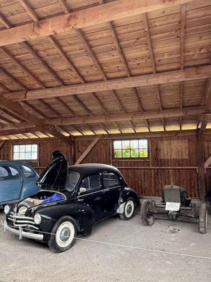 deux vieilles voitures garées dans un garage, avec un homme debout à côté d'elles