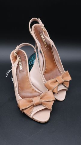 PRADA – Paire d’escarpins en cuir verni beige, nœuds gold piqué s...