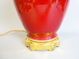 a red vase with a gold base on a white surface