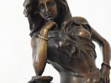 statue of a woman sitting on a vase with her hand on her chin