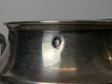 a large silver pot with a handle on a table